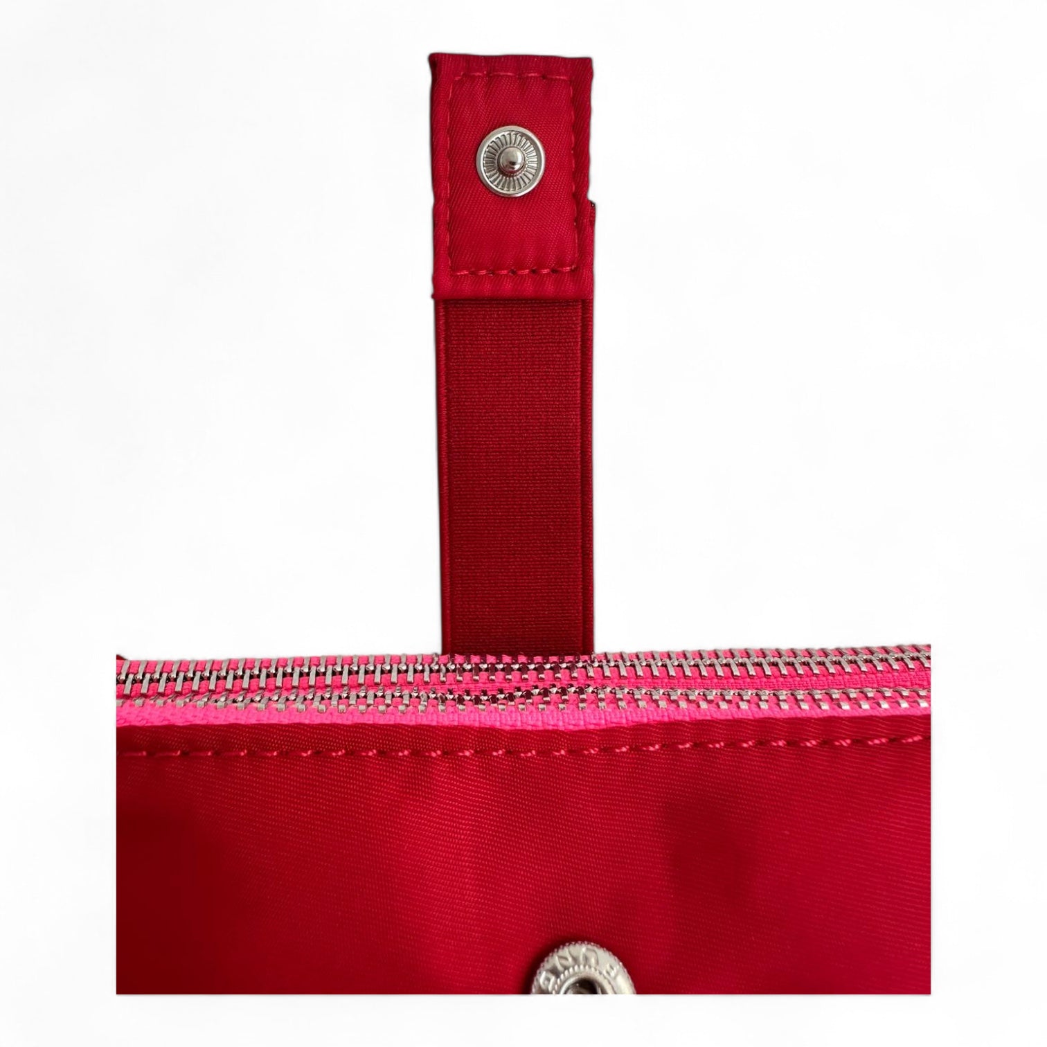 Close-up of a red bag with a zipper and strap on a white background